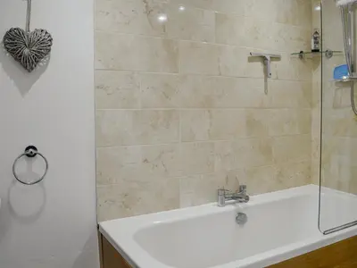 a bathroom with a shower and a tub and a sink at Howbeck Cottage in Hesket Newmarket