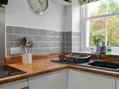 a kitchen with a sink and a clock on the wall at Howbeck Cottage in Hesket Newmarket