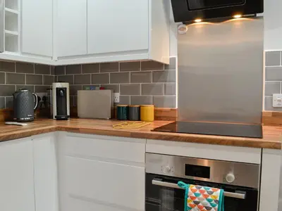 a kitchen with white cabinets and a stainless steel refrigerator at Howbeck Cottage in Hesket Newmarket