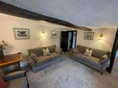 a living room with two couches and a table at Seatoller House in Borrowdale Valley