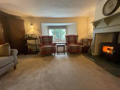 a living room with two chairs and a fireplace at Seatoller House in Borrowdale Valley