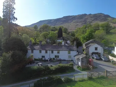 an aerial view of a house with a mountain in the background at Seatoller House in Borrowdale Valley