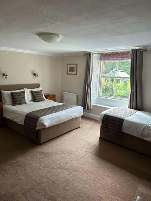 a bedroom with two beds and a window at Seatoller House in Borrowdale Valley