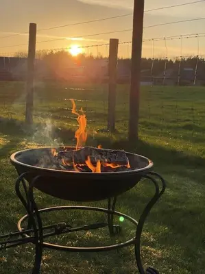a barbecue grill with a fire in a field at Courtyard Cottage in Lockerbie