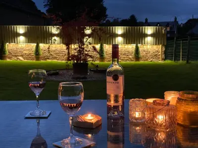 a bottle of wine and two glasses on a table at Courtyard Cottage in Lockerbie