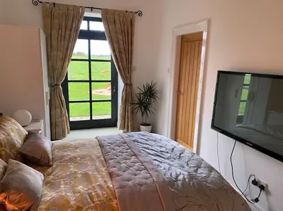 a bedroom with a large bed and a large window at Courtyard Cottage in Lockerbie