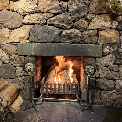 a stone fireplace with a fire in it at Royal Oak Braithwaite in Keswick