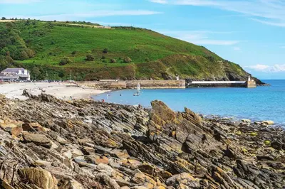 a beach with a train on a hill next to the water at The Workshop, Bridge House in Laxey