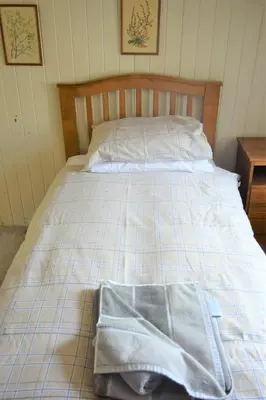 a bed with two towels sitting on top of it at Grooms Cottage in Carsethorn