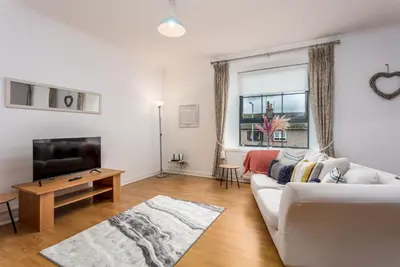a living room with a white couch and a tv at No27 The Barclay - Donnini Apartments in Kilmarnock