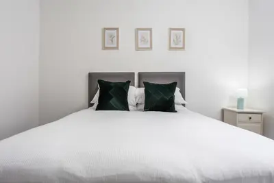 a bedroom with a large white bed with green pillows at No27 The Barclay - Donnini Apartments in Kilmarnock