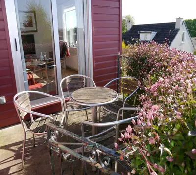 a table and chairs on a porch with flowers at Arakhova in Kirkcudbright