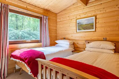 two beds in a log cabin with a window at Screel View in Kippford