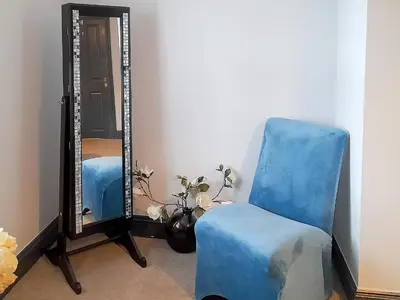 a blue chair sitting in front of a mirror at Willow Cottage in Cockermouth