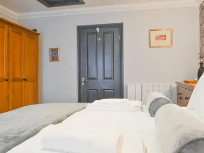 a bedroom with a white bed with a black door at Willow Cottage in Cockermouth