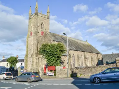 an old church with cars parked in front of it at Willow Cottage in Cockermouth