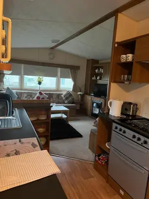 a kitchen with a stove and a living room at Coyles retreat in Stranraer