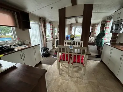 a kitchen with a table and a woman standing in the kitchen at Coyles retreat in Stranraer