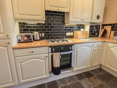 a kitchen with white cabinets and a stove top oven at Peak View in Keswick