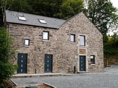 a brick building with two garage doors and windows at Waterfall in Castle Douglas