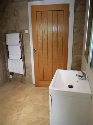 a bathroom with a white sink and a wooden door at Waterfall in Castle Douglas