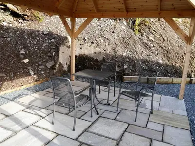 three chairs and a table under a gazebo at Waterfall in Castle Douglas