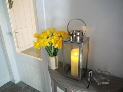 a candle and flowers on a table with a vase at Waterfall in Castle Douglas