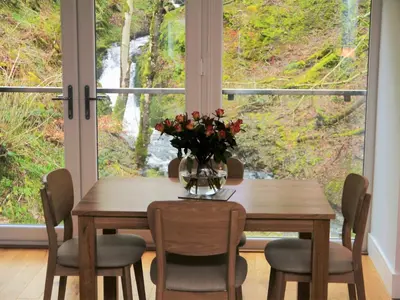 a dining room table with a vase of flowers at Waterfall in Castle Douglas