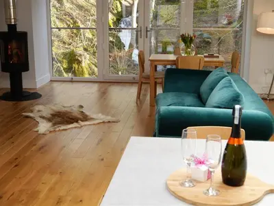 a living room with a couch and a table with wine glasses at Waterfall in Castle Douglas