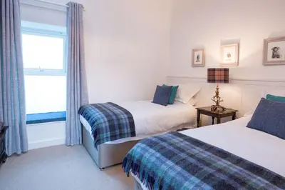 a bedroom with two beds and a window at Grobdale Byre in Gatehouse of Fleet