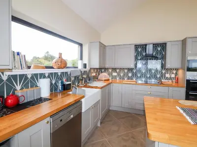 a kitchen with white cabinets and a large window at The Lodge in Stranraer
