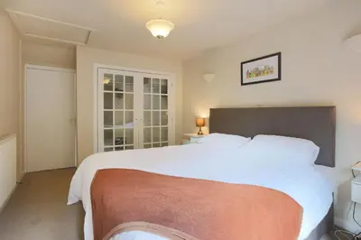 a bedroom with a large bed with white sheets at Silver Lodge in Creetown