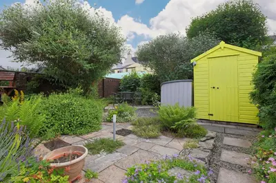 a yellow shed in the middle of a garden at Silver Lodge in Creetown