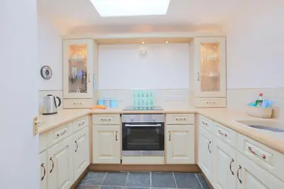 a kitchen with white cabinets and a sink and a stove at Silver Lodge in Creetown