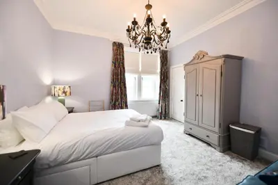 a bedroom with a white bed and a chandelier at The Old Manse in Ayr