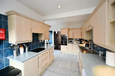 a large kitchen with wooden cabinets and black appliances at The Old Manse in Ayr
