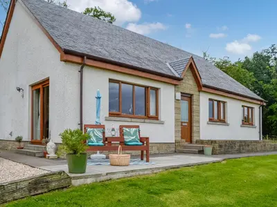 a small white house with a bench in a yard at Trelaw - Uk41532 in Cumnock