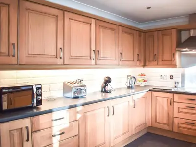 a kitchen with wooden cabinets and a sink and a microwave at Trelaw - Uk41532 in Cumnock