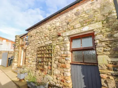 a stone building with a door and a window at Swallow Barn in Cockermouth