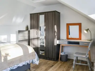 a bedroom with a bed and a desk with a mirror at Cowar Bothy in Dalbeattie