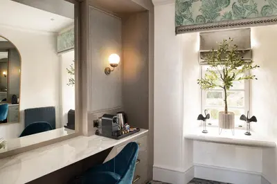 a hotel room with a mirror and a blue chair at Brig o' Doon House Hotel in Ayr