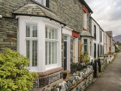a row of houses with white shutters on a street at Derwent Cottage in Keswick