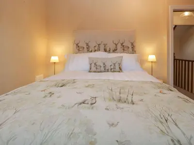 a bedroom with a large white bed with two lamps at Derwent Cottage in Keswick