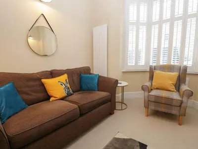 a living room with a brown couch and a chair at Derwent Cottage in Keswick