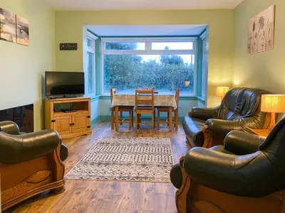 a living room with a table and chairs and a television at Ardwell Park in Ardwell