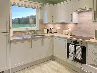 a kitchen with white cabinets and a sink and a window at Ardwell Park in Ardwell