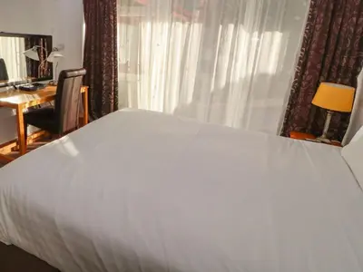 a bedroom with a white bed with a desk and a window at Old School Muncaster House in Ravenglass
