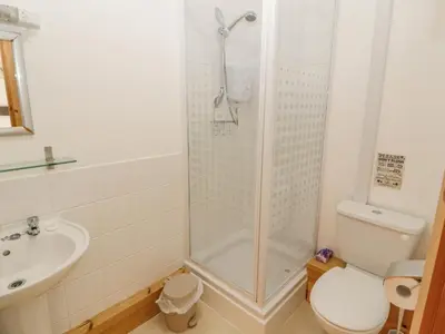 a bathroom with a shower and a toilet and a sink at Old School Muncaster House in Ravenglass