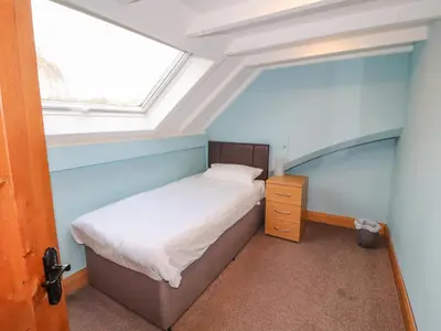 a small bedroom with a bed and a window at Old School Muncaster House in Ravenglass