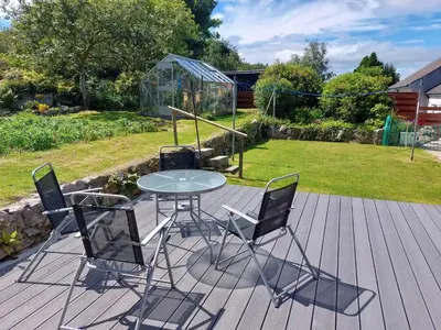 a table and chairs on a deck with a garden at Springfield in Dalbeattie